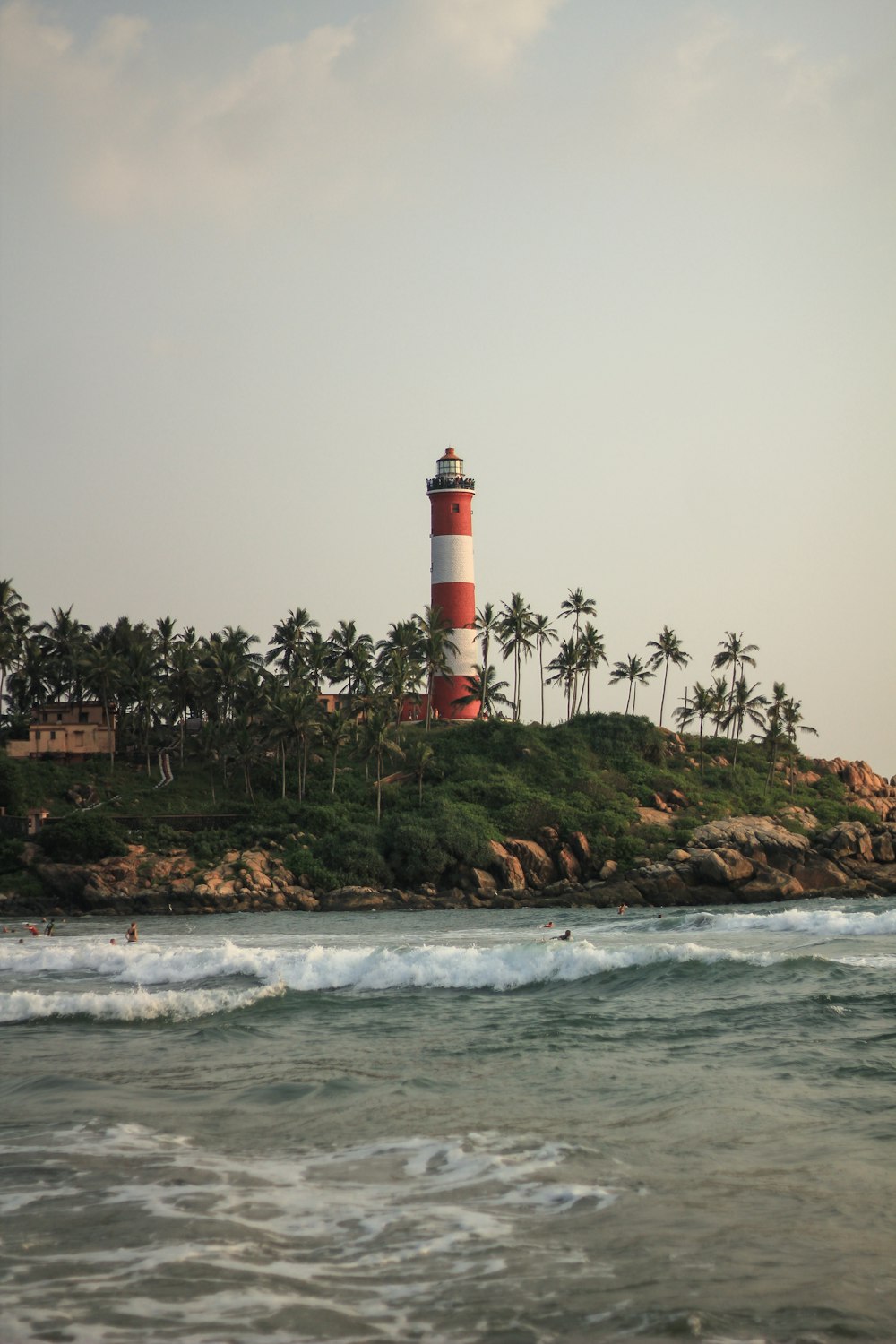 white and red lighthouse on brown rock formation near body of water during daytime