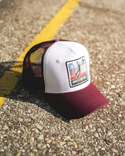 A modern snapback cap featuring subtle branding, resting on a graffiti-covered metal fence.