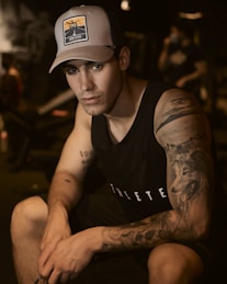 man in black tank top wearing white cap
