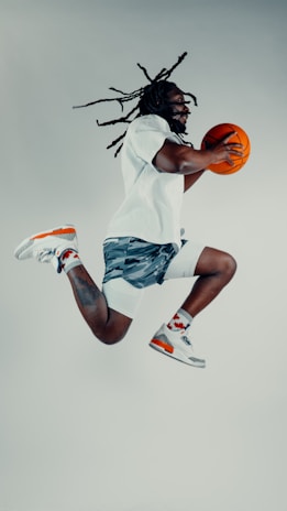 Athlete wearing knee supports mid-jump during a basketball game, showing shock absorption.