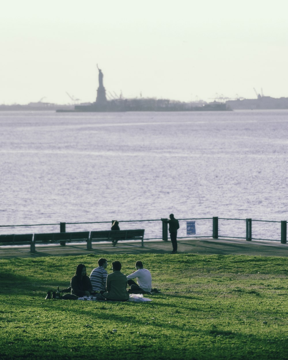 people sitting on green grass field near body of water during daytime