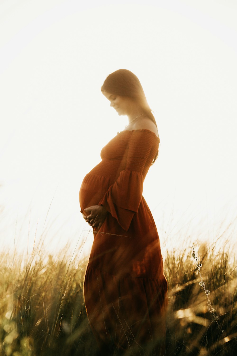 woman in brown dress standing on grass field during daytime