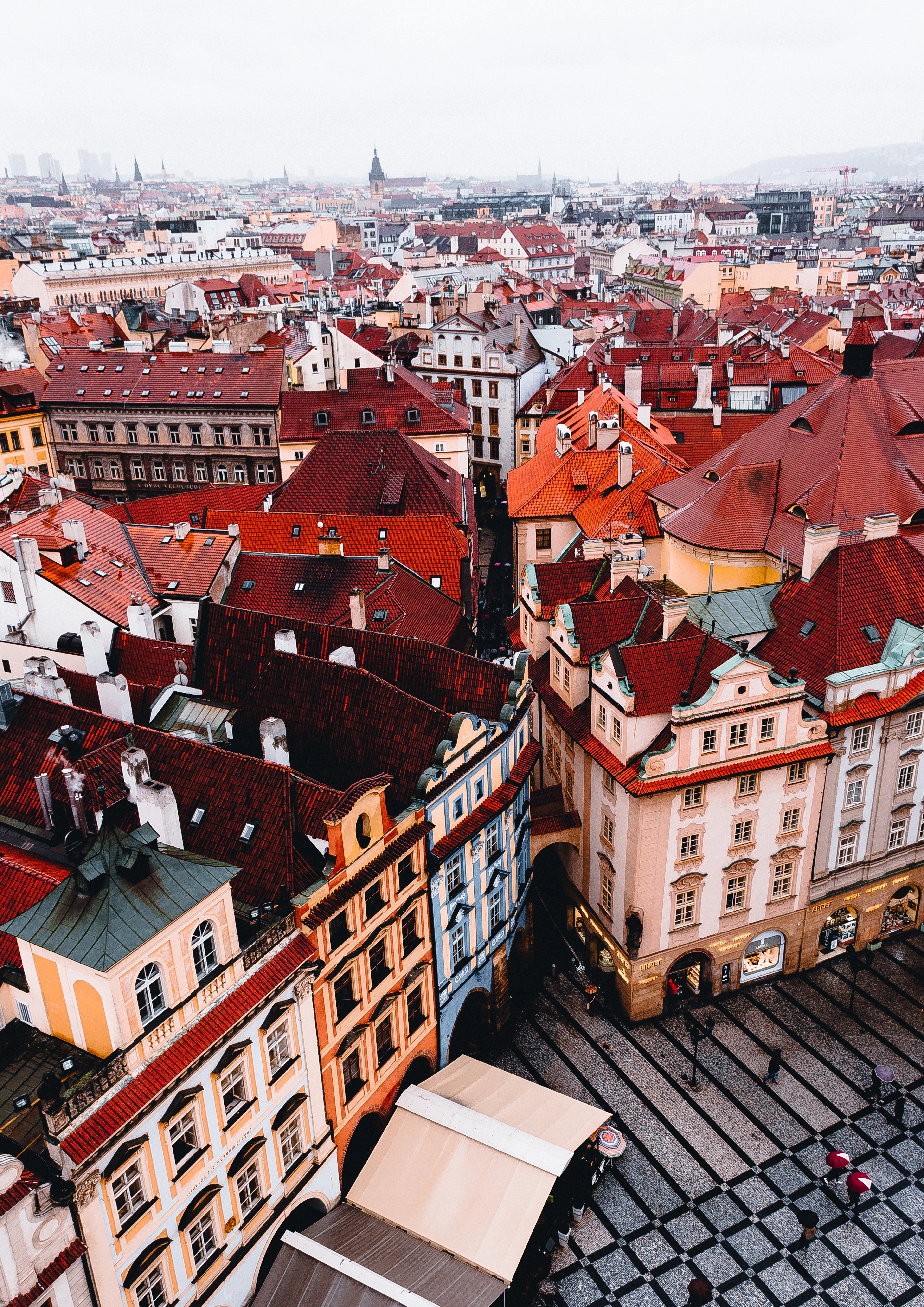 A dense pattern of red-tiled rooftops and narrow lanes in Prague's Old Town, seen from above.