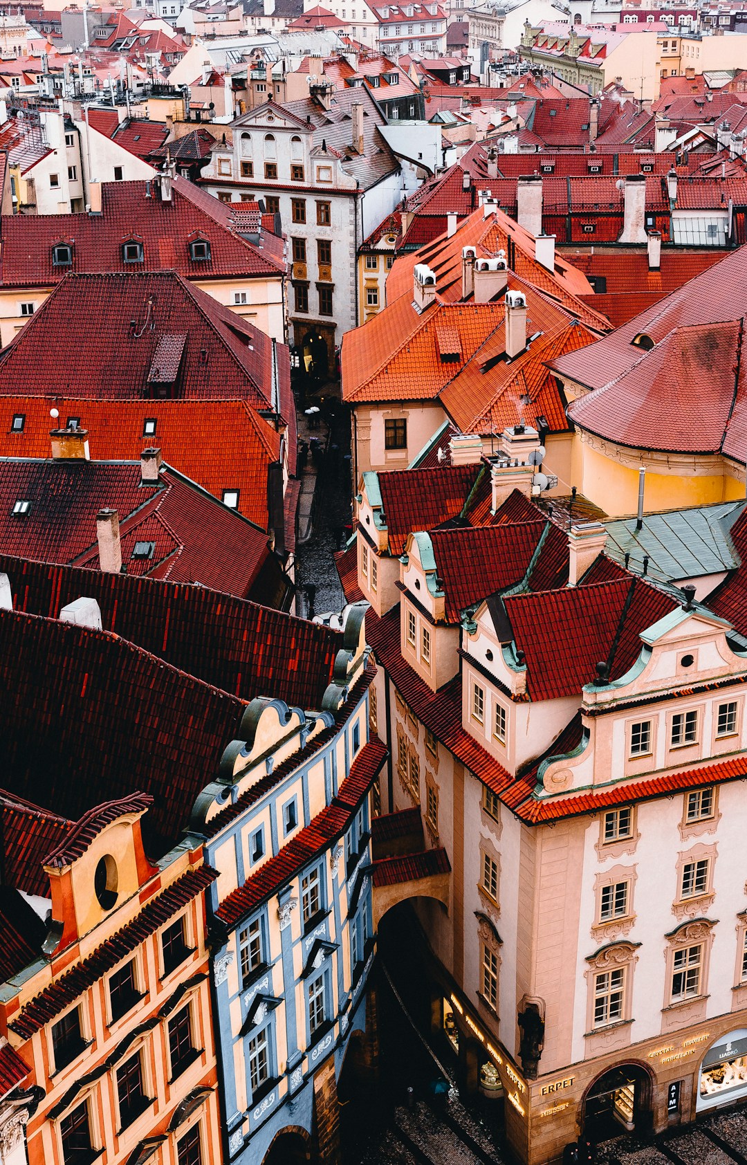 Prague - A view of Prague's old town featuring creamy stucco buildings and terracotta tiled roofs under a soft sky.