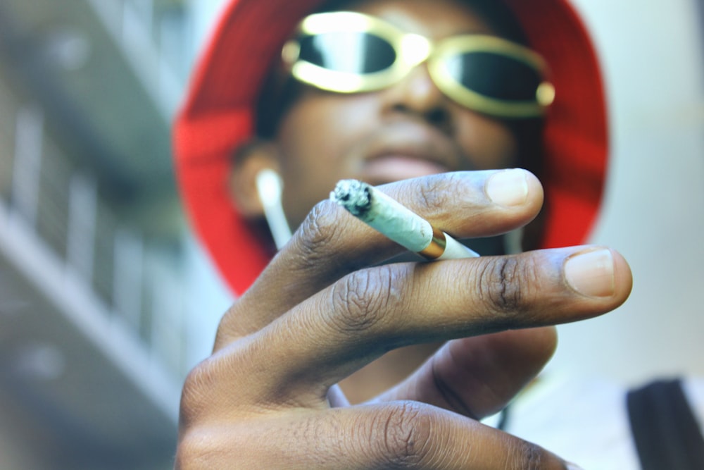 person holding cigarette stick wearing sunglasses