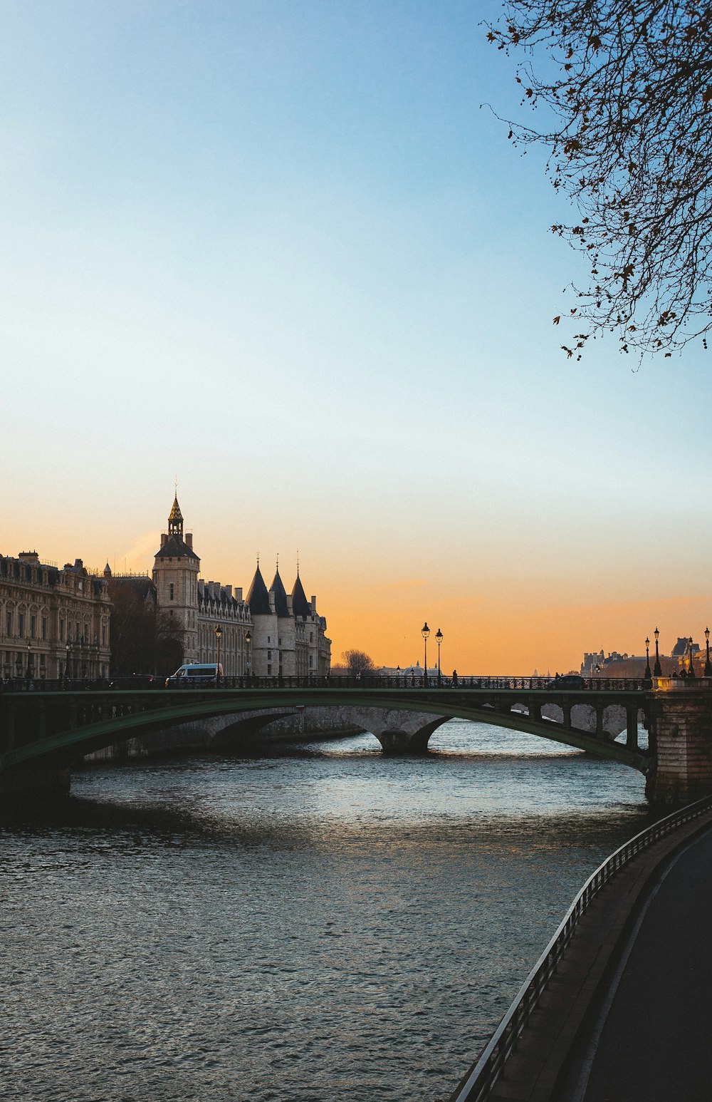 bridge over river near city buildings during sunset