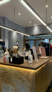 A modern cafe owner arranging Airtis water bottles on a sleek counter with soft aqua blue accents.