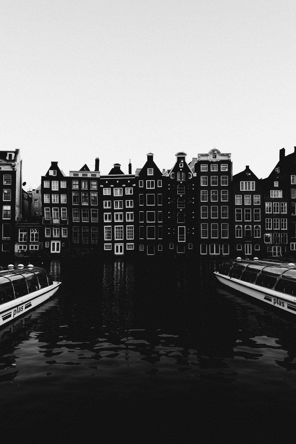 grayscale photo of city buildings near body of water