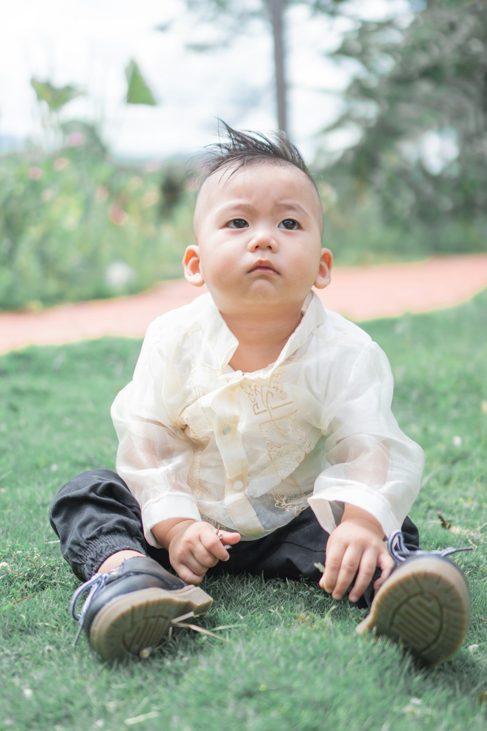 boy in white dress shirt and blue denim jeans sitting on green grass during daytime