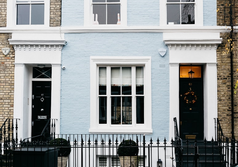 Elegant exterior of a modern London townhouse with deep navy blue door and gold accents.