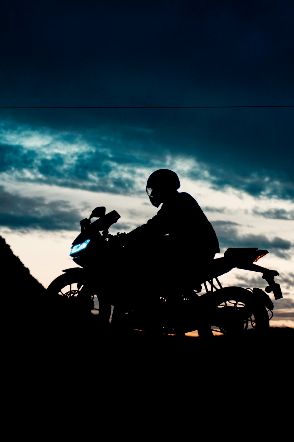 uomo in giacca nera che guida la moto durante il giorno