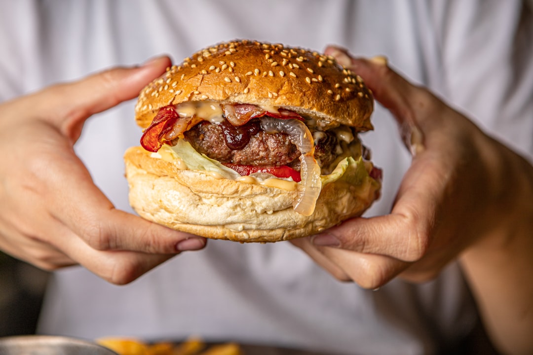 person holding burger with patty and lettuce