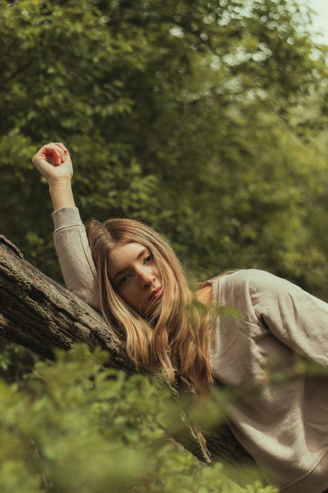 woman in white long sleeve shirt holding tree branch during daytime