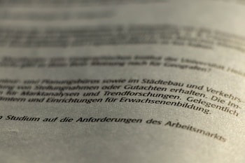 A close-up view of a printed German text, slightly blurred in the foreground and background, with a focus on the middle section. The document appears to be formal or academic in nature.
