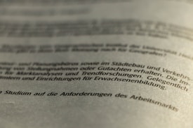 A close-up view of a printed German text, slightly blurred in the foreground and background, with a focus on the middle section. The document appears to be formal or academic in nature.