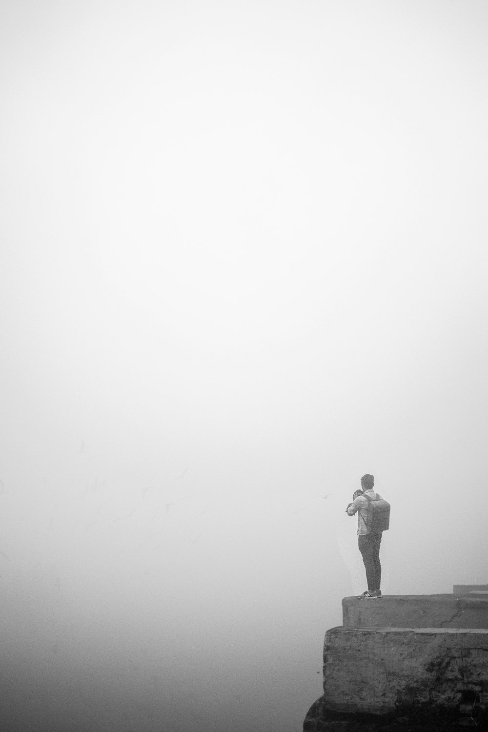 man in black jacket standing on gray concrete pavement