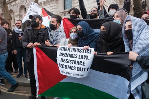 man in black jacket and black cap holding white banner