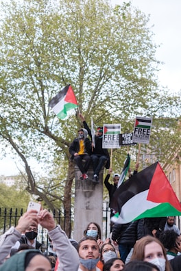 man in black and yellow jacket holding flag