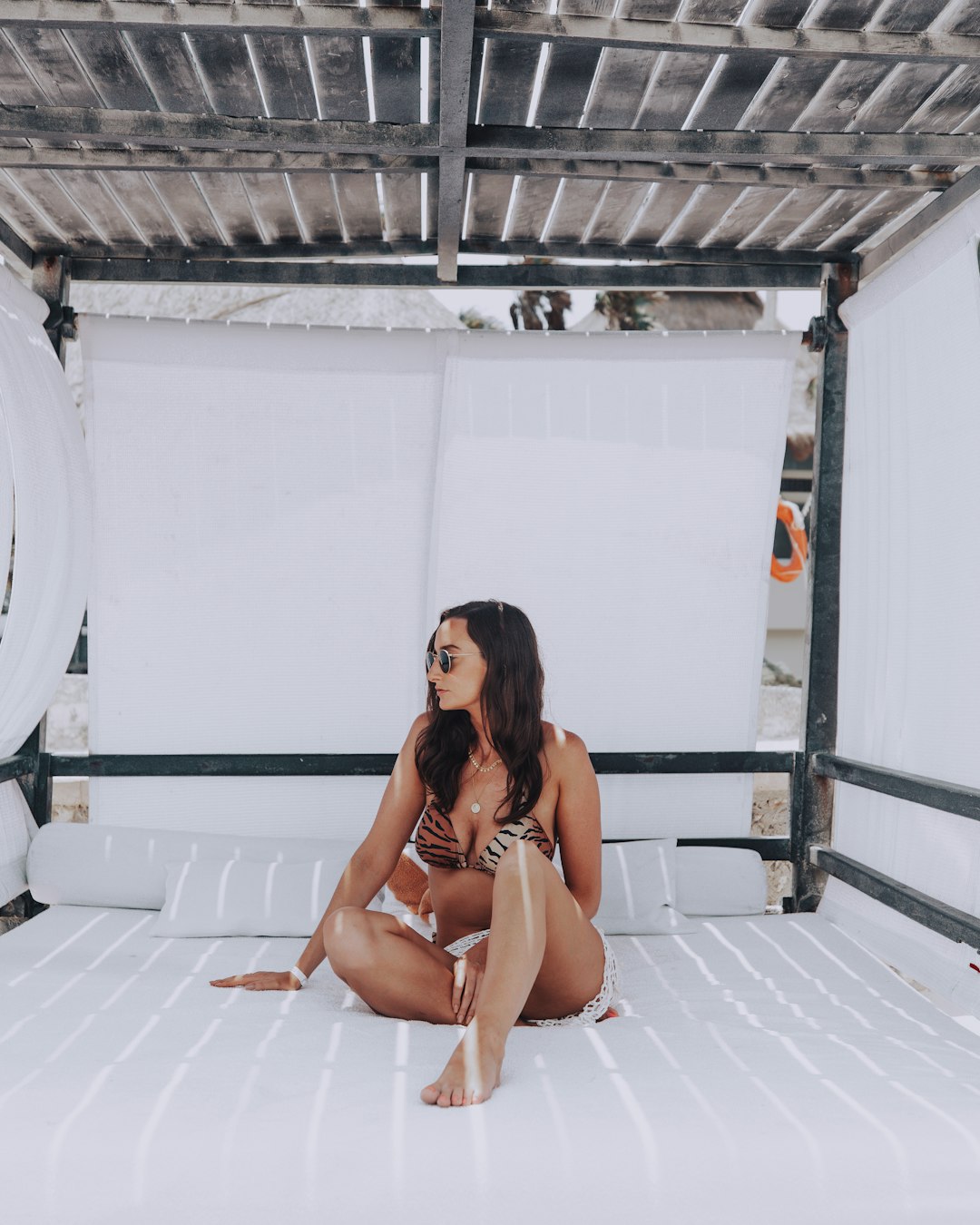 woman in white bikini sitting on white concrete wall during daytime