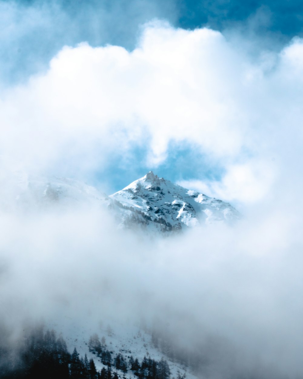 Schneebedeckter Berg tagsüber unter weißen Wolken