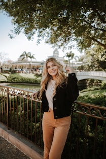 woman in black jacket and brown pants standing on bridge during daytime