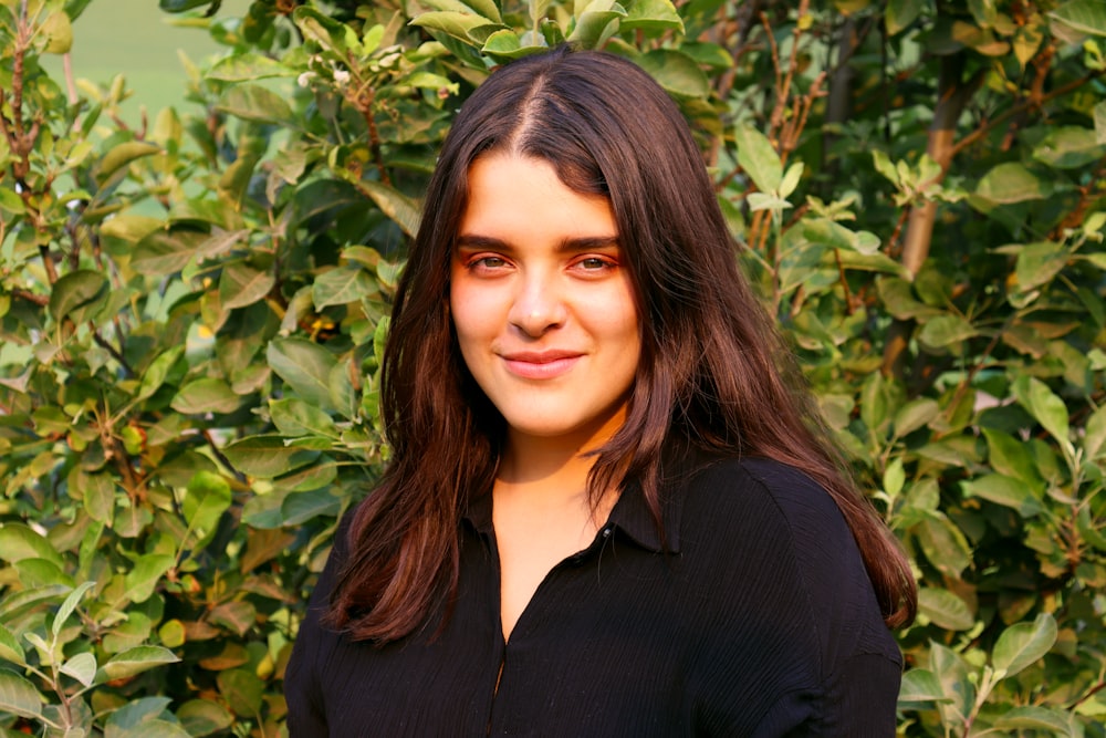 woman in black v neck shirt standing beside green plant