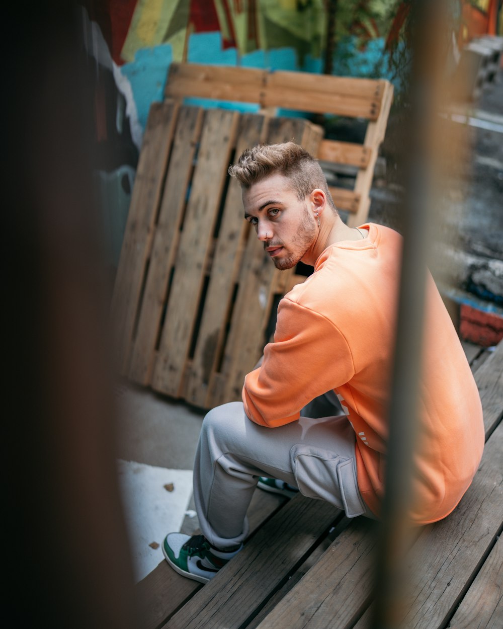 man in orange polo shirt sitting on floor