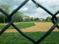 Local children playing baseball in a dusty neighborhood field under a clear blue sky.