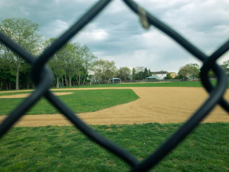 Local children playing baseball in a dusty neighborhood field under a clear blue sky.