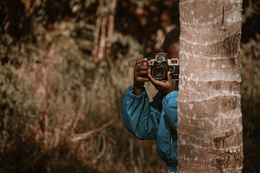 man in blue jacket holding black dslr camera