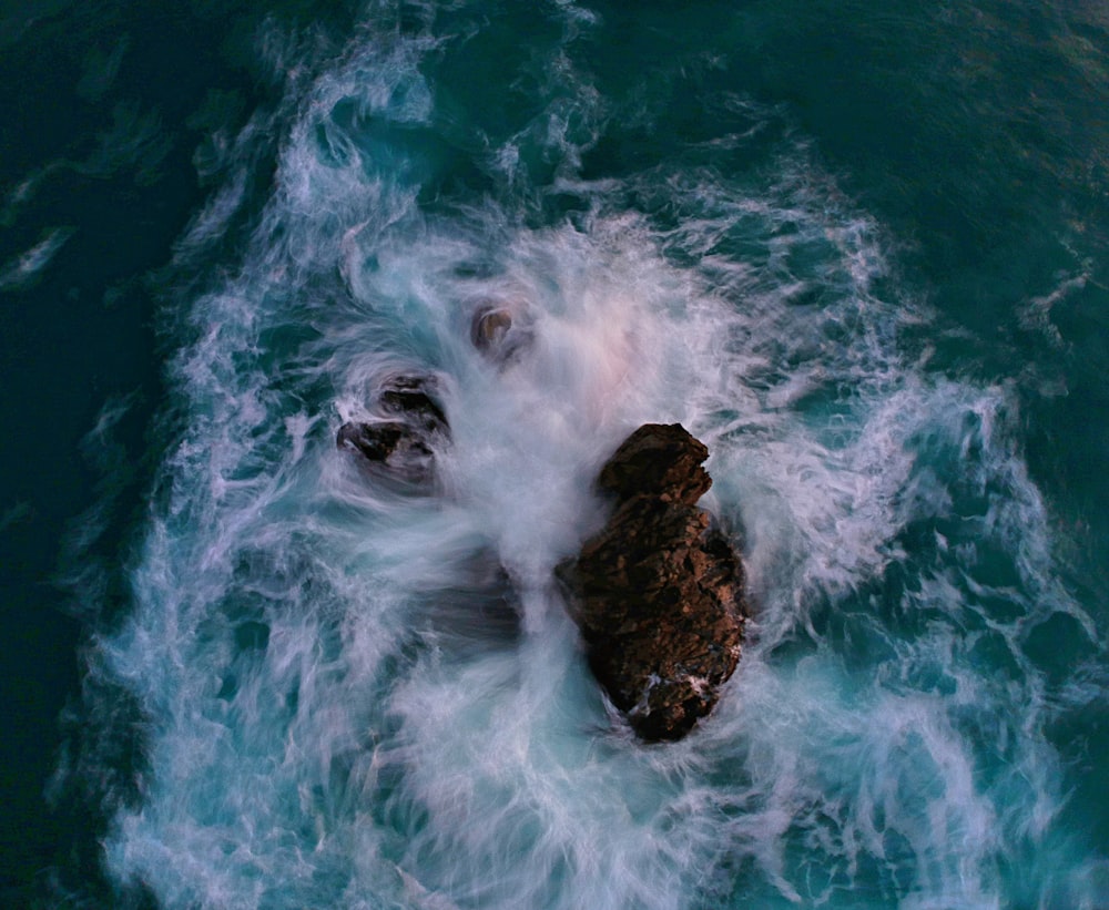 brown rock formation on body of water during daytime