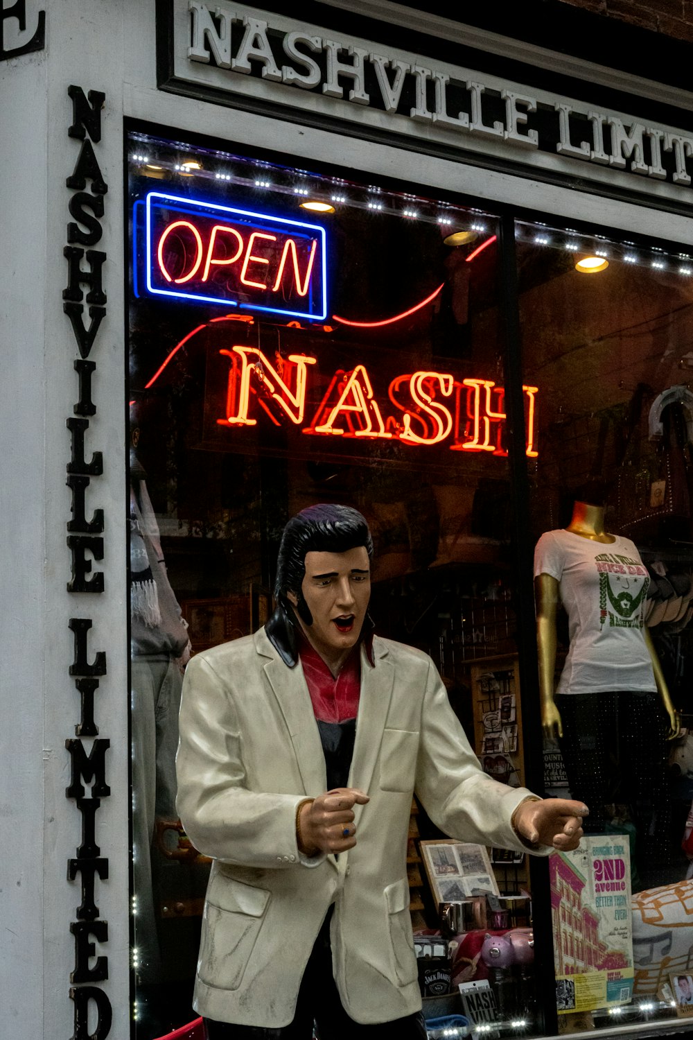 man in white coat and black knit cap standing near store