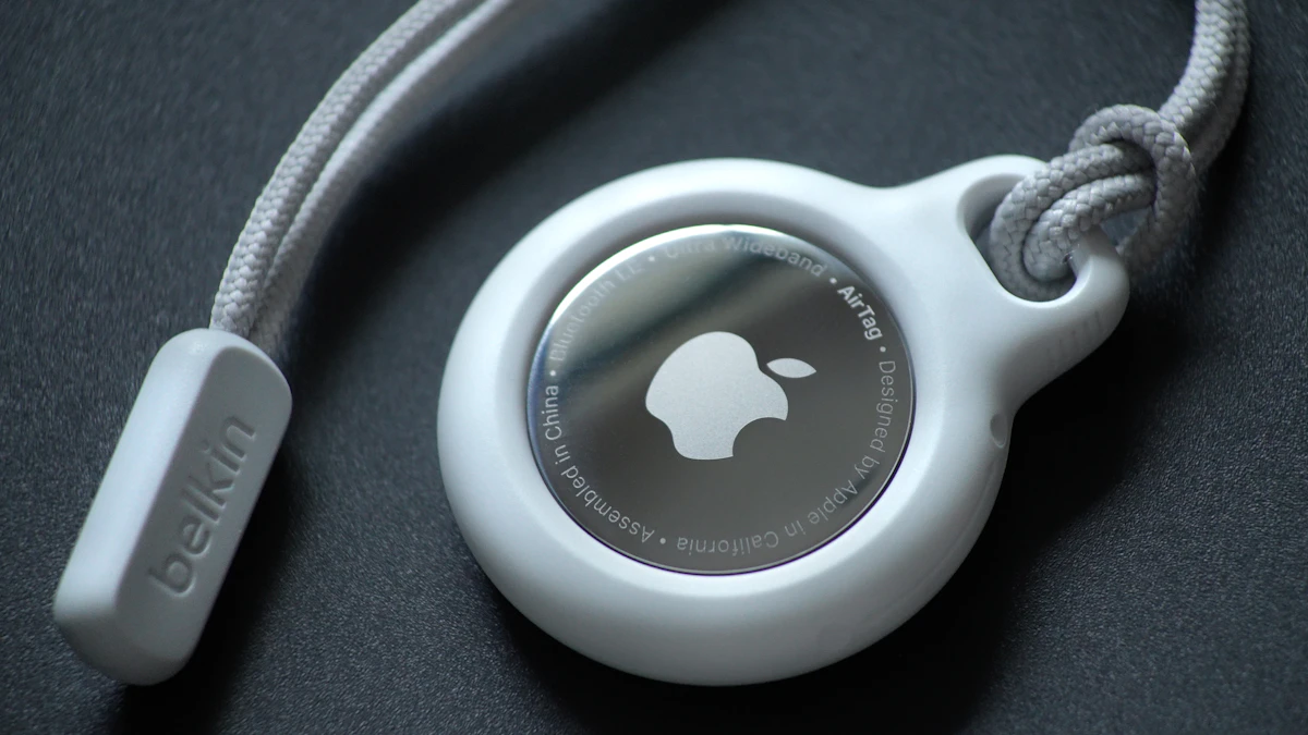 Apple AirTag with a Belkin loop accessory on a dark surface, ready to attach to keys or a bag