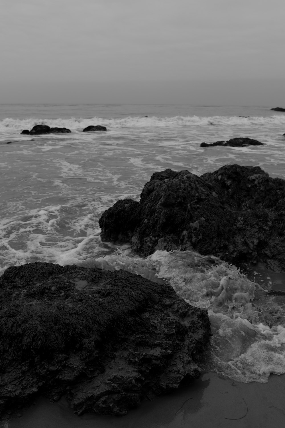 grayscale photo of sea waves crashing on rocks