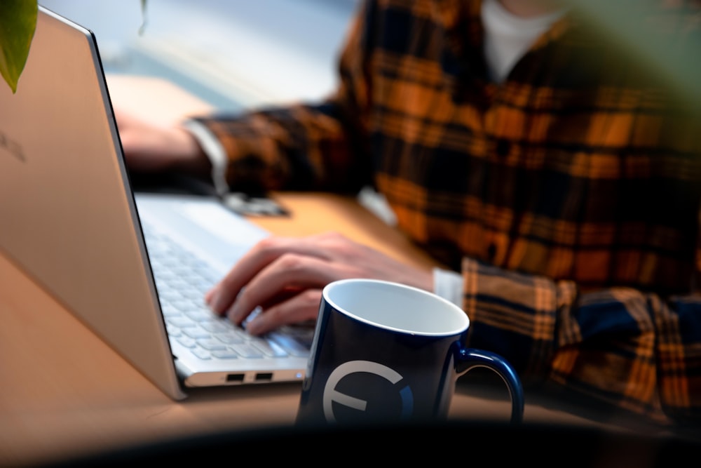 Person in braun-schwarz kariertem Hemd mit MacBook Air