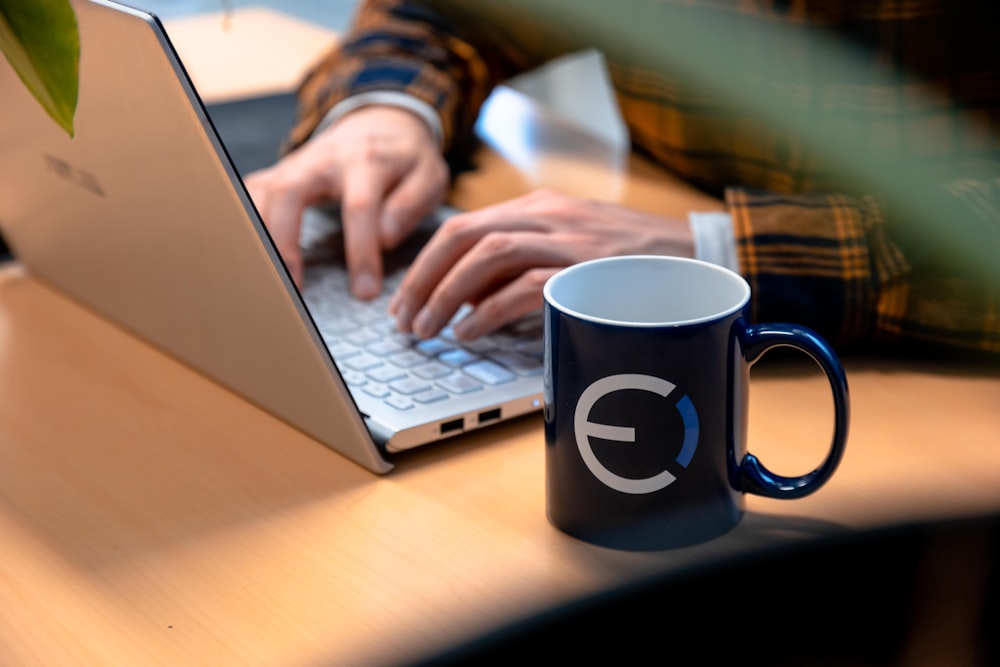 black and white ceramic mug beside macbook pro