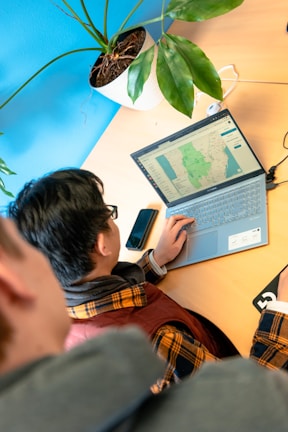 A logistics coordinator planning routes with maps and a laptop.
