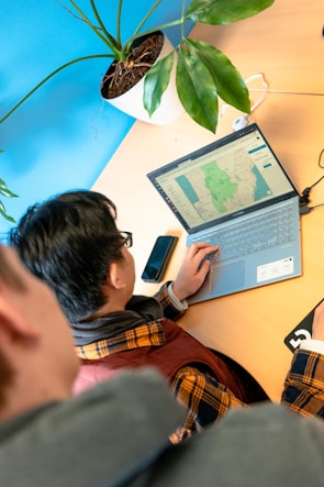 Close-up of a journalist typing on a laptop with a world map showing oceans in blue and lands in green and yellow in the background.