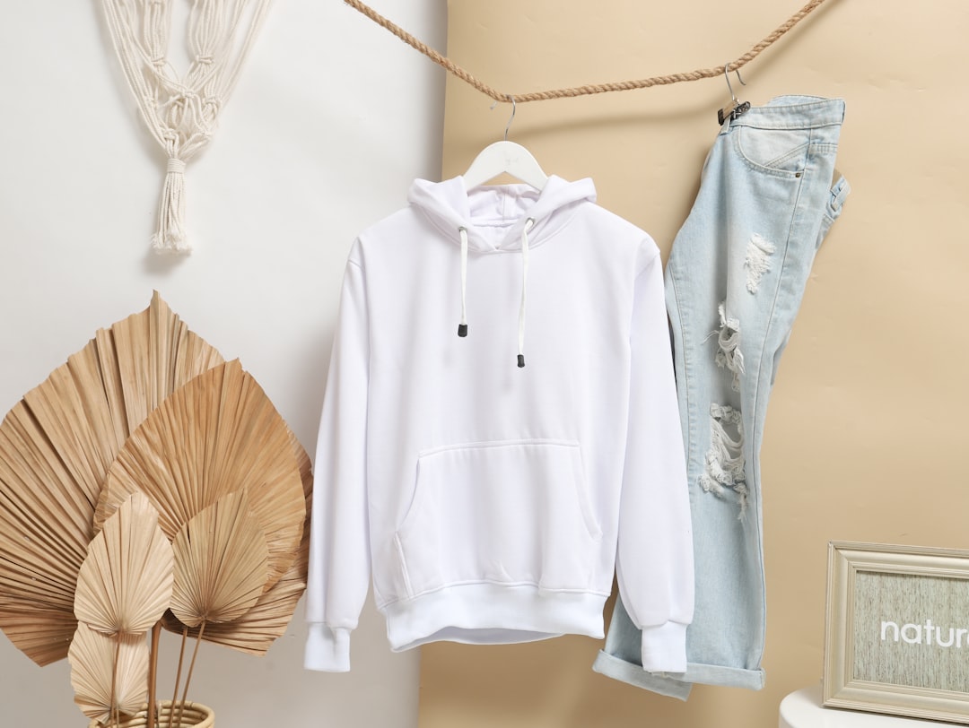 white zip up jacket hanging on brown wooden clothes hanger, Plain white hoodie hanging on a studio background with jeans