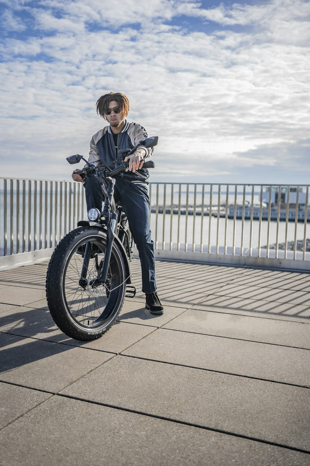 woman in black jacket and blue denim jeans riding bicycle during daytime