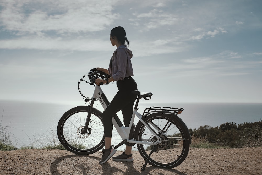 Hombre con camisa blanca y pantalones cortos negros montando bicicleta negra durante el día