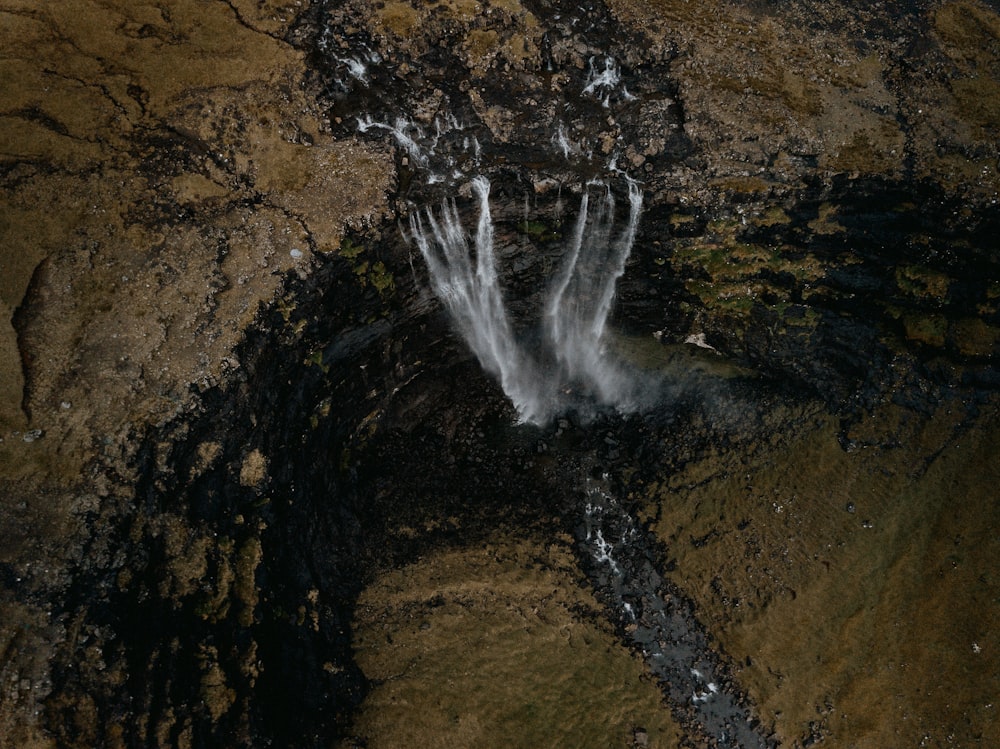 water falls on brown rocky mountain