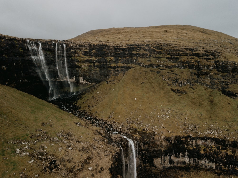 waterfalls on brown rocky mountain during daytime