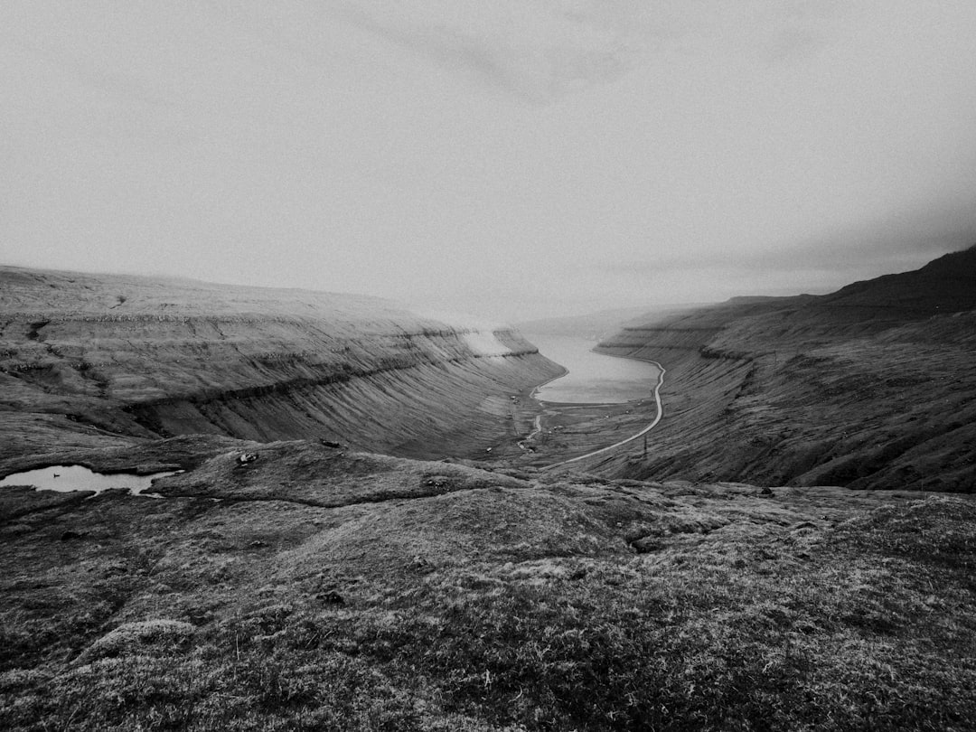 grayscale photo of mountain near body of water