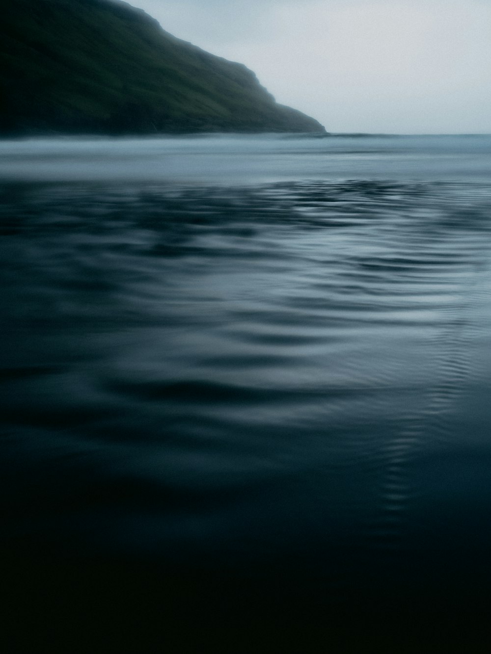 body of water near mountain during daytime