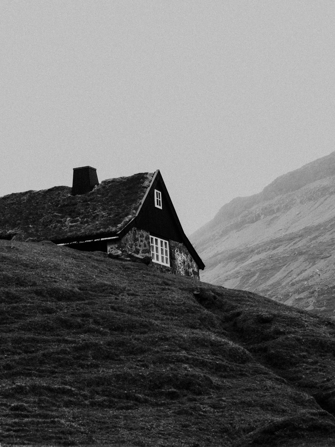 grayscale photo of house on hill