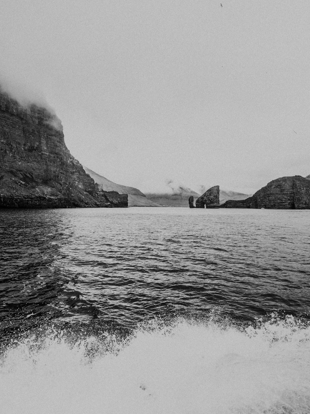 grayscale photo of body of water near mountain