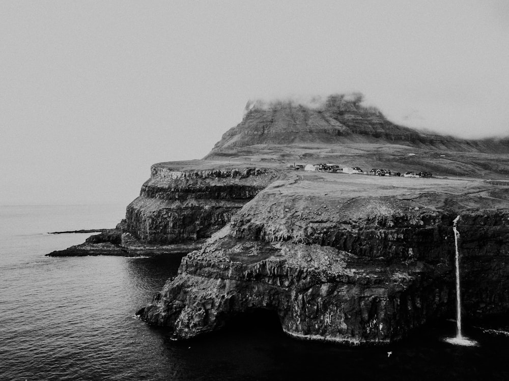 grayscale photo of rock formation near body of water