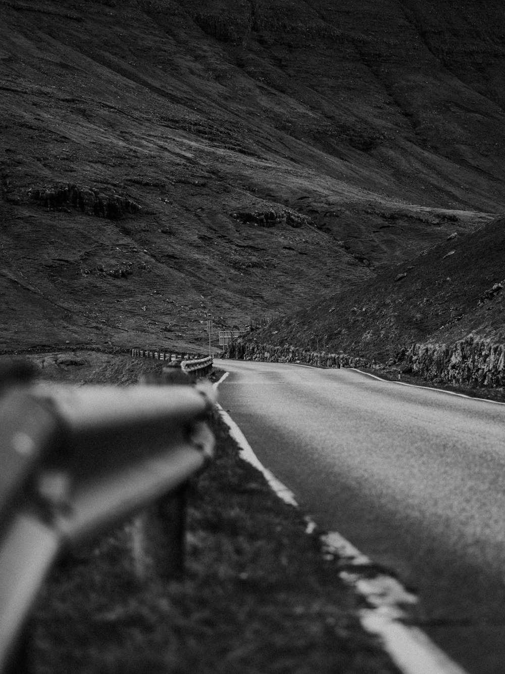 grayscale photo of road between mountains