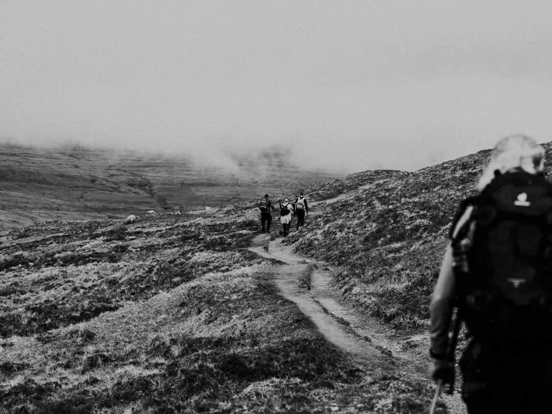 grayscale photo of 2 people walking on dirt road,